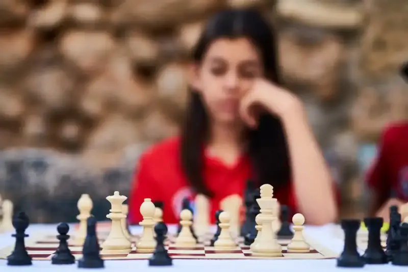 Niña pensativa frente a un tablero de ajedrez, inmersa en los juegos de decisiones.